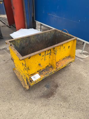 a yellow dumpster sitting in front of a blue wall