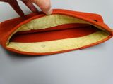 a person that is holding an orange purse on a table