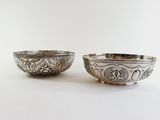 pair of silver plated bowls with floral designs on the sides