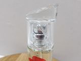 a small glass bottle with a red flower on it