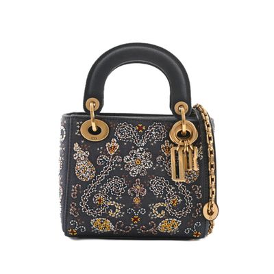 a black handbag with a gold chain and a flower design