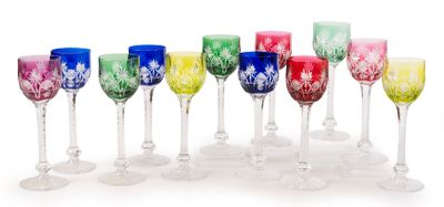 twelve colorful wine glasses lined up in a row on a white surface