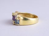 a close up of a gold ring with a purple and blue stone