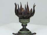 a metal vase with a flower on it on a table