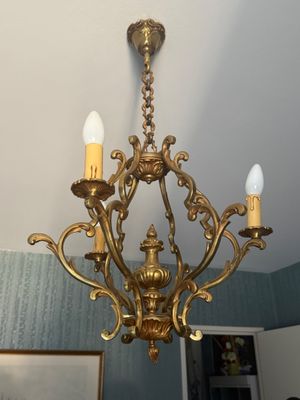 un lustre en or auquel sont suspendues trois bougies