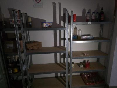 many shelves with bottles and cans on them in a room