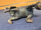 a bronze statue of a dog with a flower in its mouth