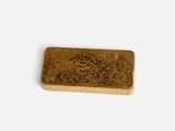 a close up of a piece of gold colored soap on a white surface