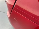 a close up of a red car with a hole in the side