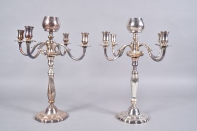 pair of silver plated candelabs with candles on each of them