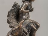 bronze statue of a woman sitting on a shell with a bird on her back
