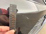 a person that is holding a ruler in front of a car