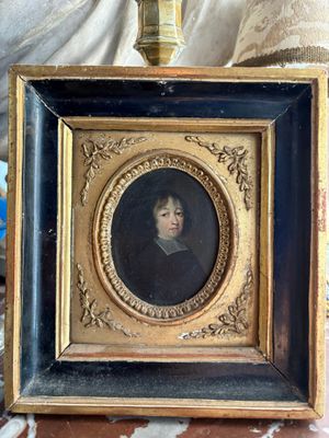 painting of a woman in a black dress in a gold frame on a table