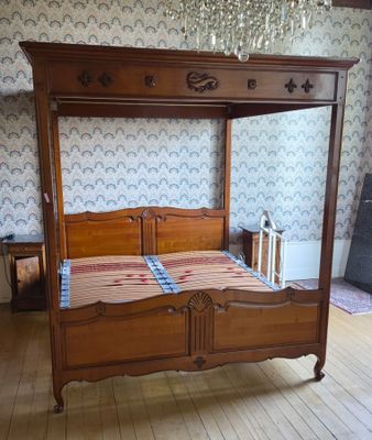 un lit avec un cadre en bois et un lustre suspendu au plafond