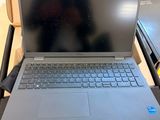 a laptop computer sitting on a desk with a bag in the background
