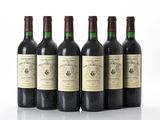 six bottles of wine are lined up in a row on a white surface