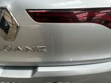 the rear end of a white car with a chrome logo