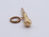 a small gold object on a white surface