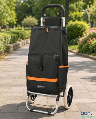 une photo d'un caddie noir et orange posé sur un trottoir