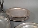 three silver plates and a silver pitcher on a table