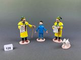 three figurines of a man with a dog and a man with a newspaper
