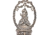 une clochette en argent richement décorée, surmontée d'une couronne