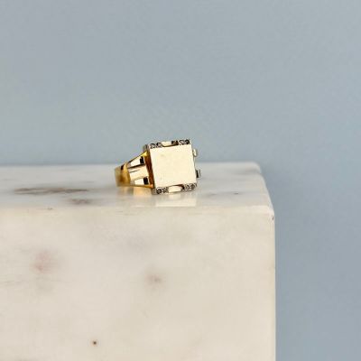 La bague en or repose sur un bloc de marbre blanc