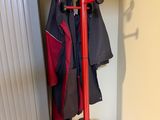 un porte-manteau sur lequel est accroché un manteau, dans un coin de la pièce