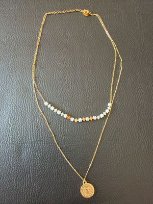 a gold necklace with a coin and a beaded chain