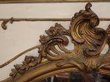 a gold mirror with a bird on top of it