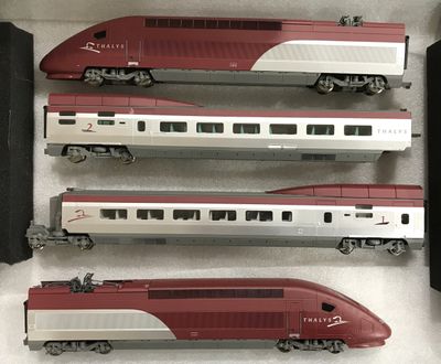 trois trains rouges et argentés posés sur une surface blanche