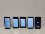 four cell phones are lined up on a table with a white background