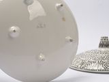 a white ball with holes on it sitting next to a white vase