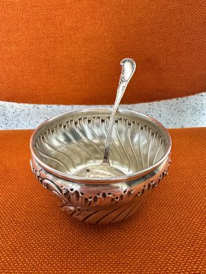 un bol en argent contenant une cuillère, posé sur une chaise orange