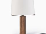 La lampe de table est en bois et est équipée d'un abat-jour blanc.