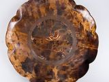 une assiette marron ornée d'un oiseau sur un fond blanc