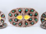 trois pièces de poterie ornées de motifs en turquoise et en or sur fond blanc