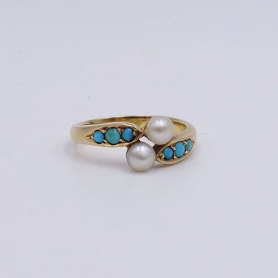 un gros plan sur une bague en or ornée de perles et de turquoises