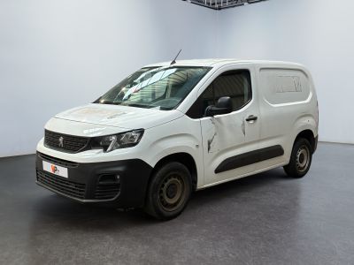 La camionnette blanche est garée dans une grande pièce au sol noir.