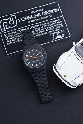 une voiture blanche et une montre noire posées sur une surface noire