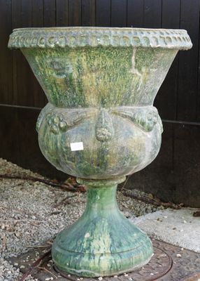 un grand vase vert posé sur une grille métallique