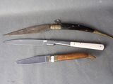 several knives are lined up on a table with a knife in the middle of them