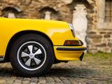 a yellow car that is parked on a cobblestone street