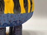a blue and yellow tiger figurine sitting on a white surface