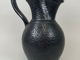 a black vase that is sitting on a white surface