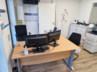 un bureau sur lequel se trouvent deux écrans d'ordinateur et une imprimante