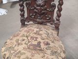 une chaise en bois sur laquelle est posé un coussin recouvert d'un tissu à motifs floraux