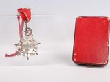 a small red box with a red ribbon and a red book with a silver star ornament hanging from it