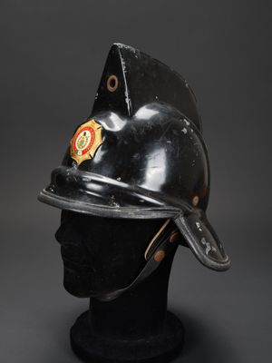 un vieux casque de pompier posé sur une tête de mannequin noire
