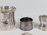 a silver cup and other silver objects on a white surface